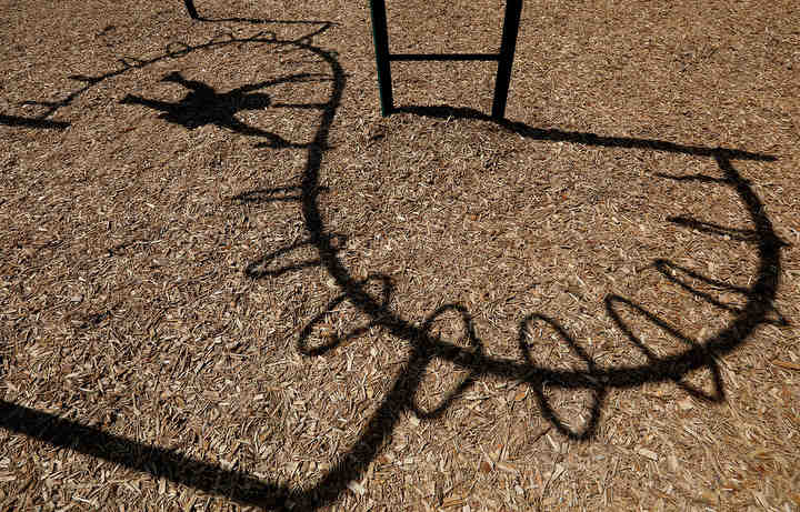 A boy climbing on monkey bars casts his shadow on the old mulch that will be replaced at the Veteran's Park playground thanks to a grant received by the National Trail Parks and Recreation District. The grant will pay for fresh fall protection at six Springfield playgrounds.   (Bill Lackey / Springfield News-Sun)